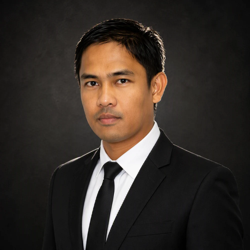 Professional studio portrait of Angelo De Ocampo in a dark suit, white shirt, and dark tie.